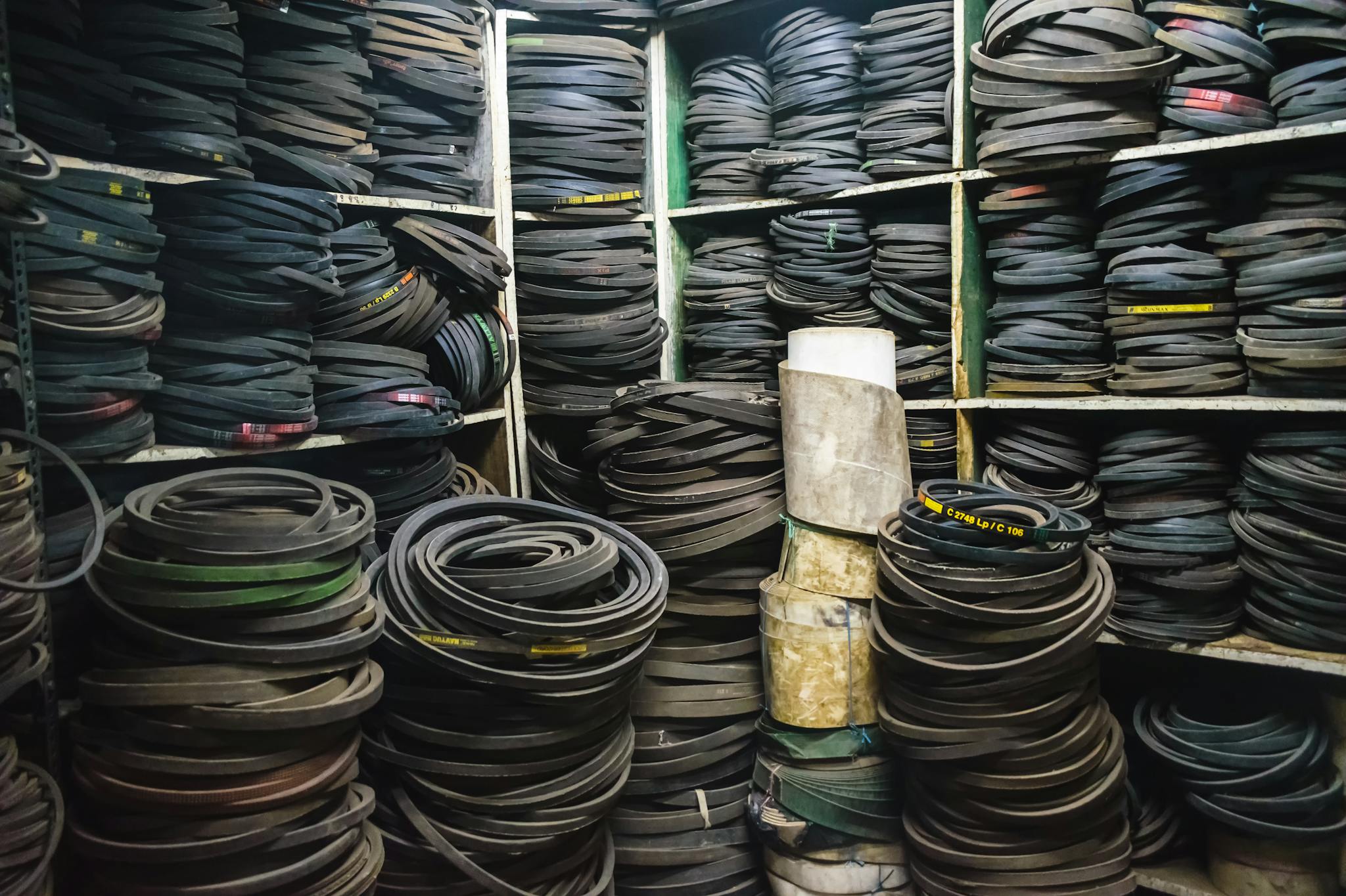 A cluttered storage room filled with stacks of rubber belts and industrial equipment.
